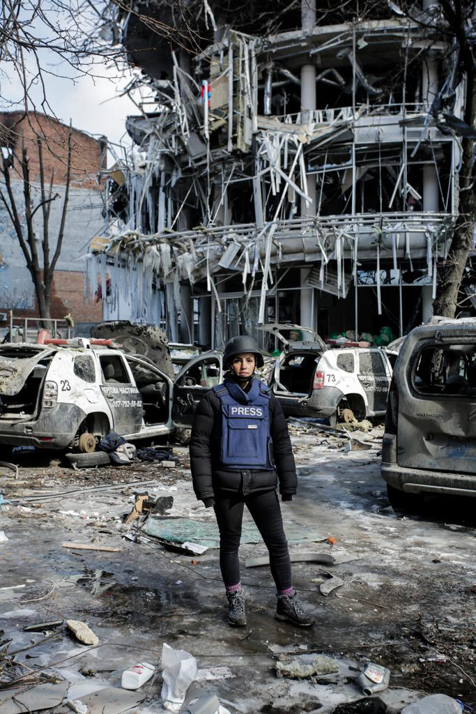 A person standing in front of a destroyed buildingDescription automatically generated with medium confidence