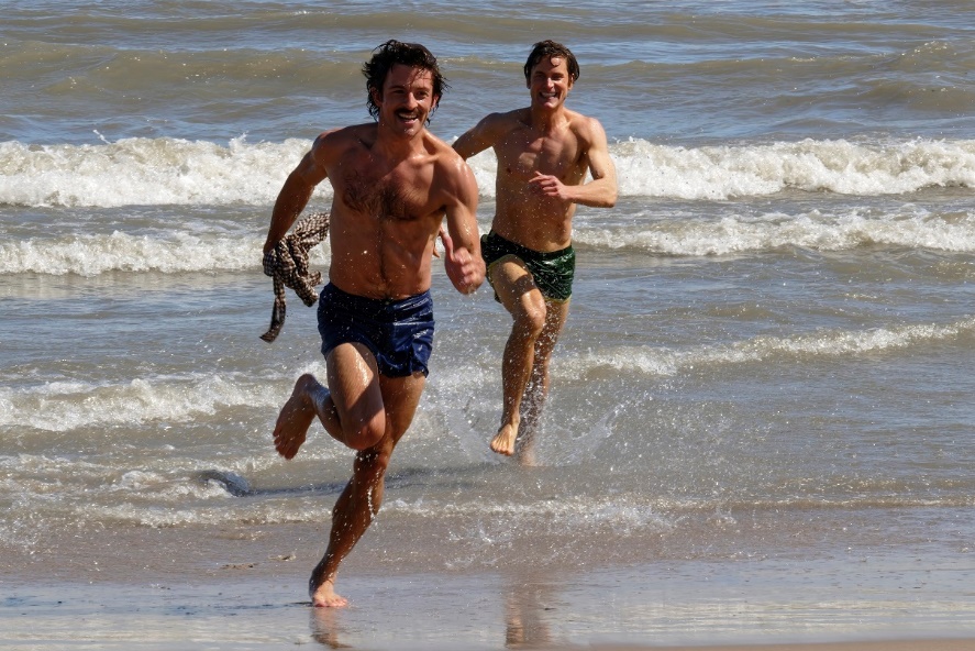 A couple of men running on a beachDescription automatically generated