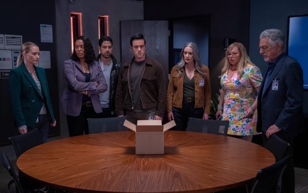 A group of people standing around a round tableDescription automatically generated
