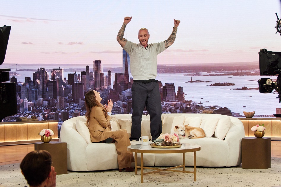A person standing on a couch with a dog and a city in the backgroundAI-generated content may be incorrect.