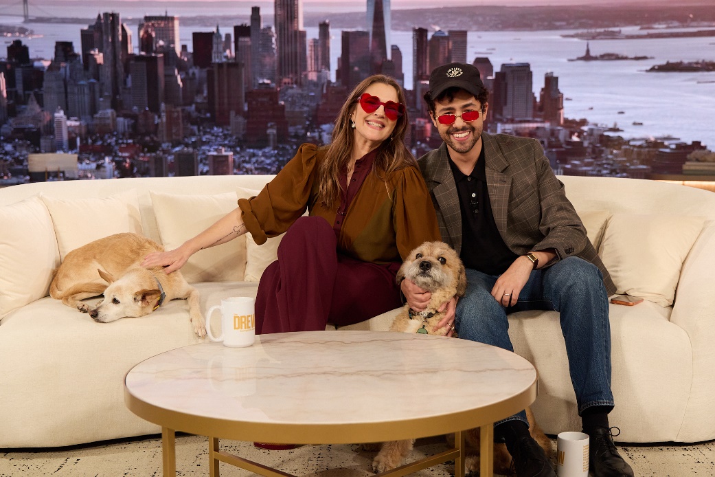 A person and person sitting on a couch with dogsAI-generated content may be incorrect.