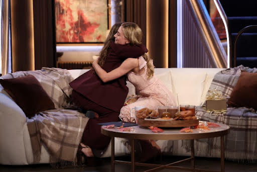 Two women hugging on a couchDescription automatically generated