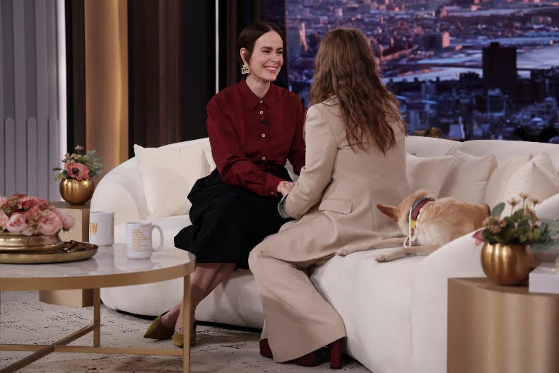 Two women sitting on a couch with a dogDescription automatically generated